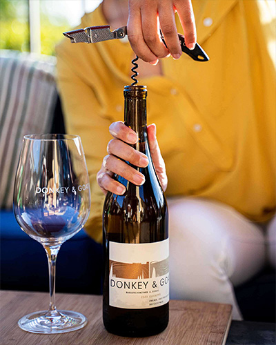 Woman opening a bottle of Donkey & Goat wine 