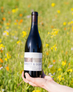 Bottle of Siletto Vineyard Negrette being held in field of flowers