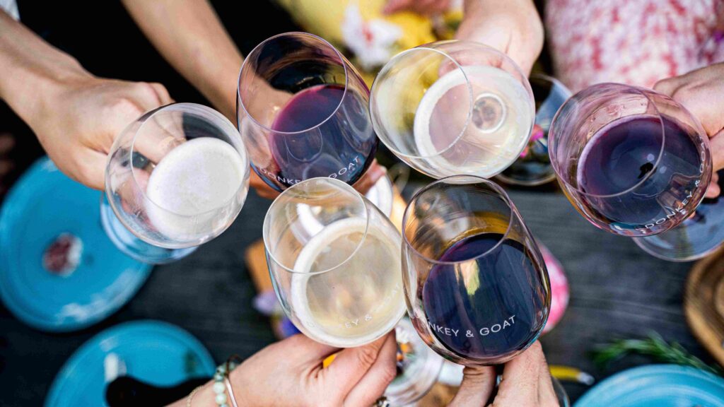 people clinking wine glasses from above