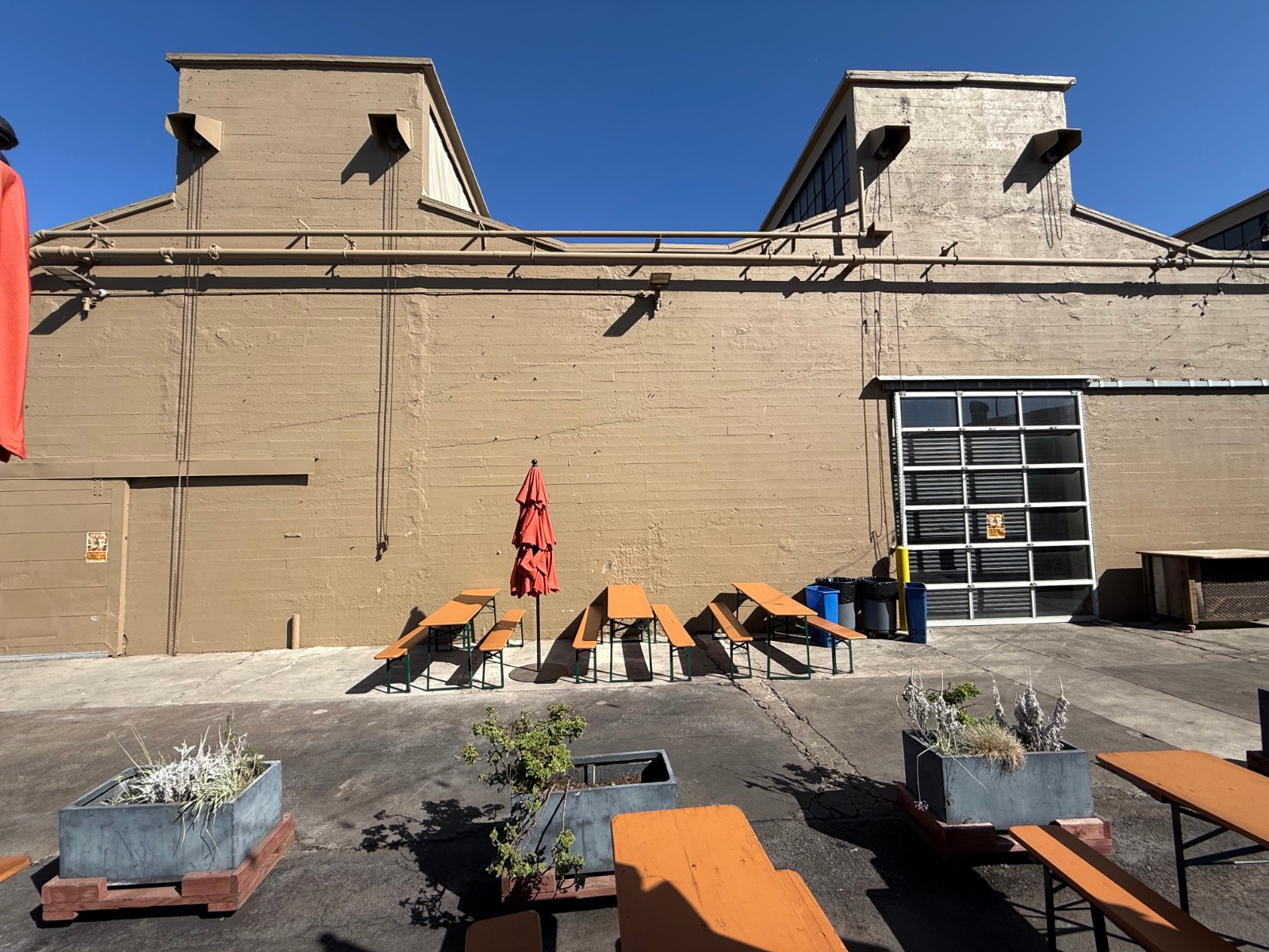 The courtyard on a sunny day: picnic tables, a red umbrella and the roll-up door