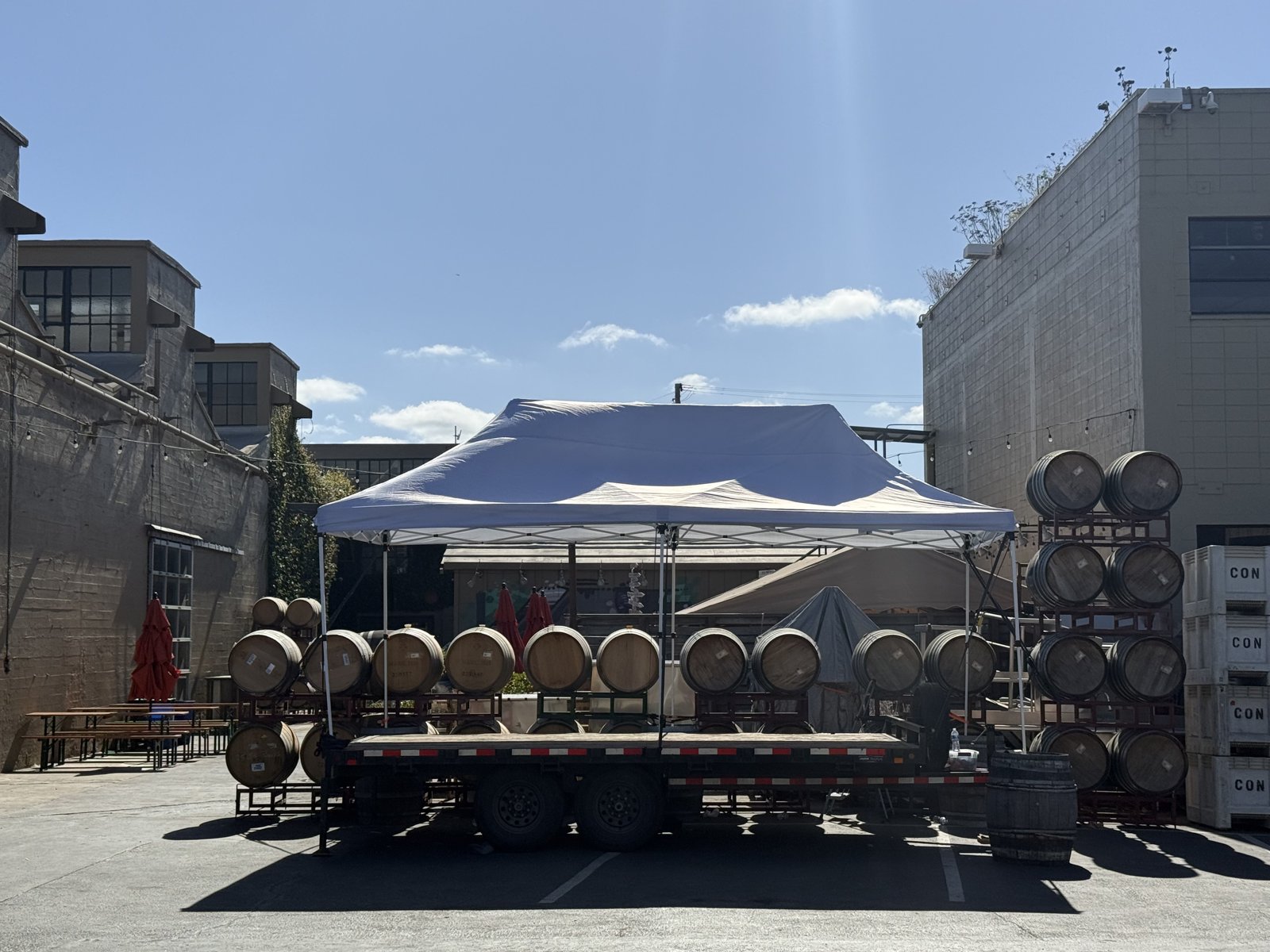 The trailer stage for bands under a canopy in the courtyard, with barrels stacked behind it