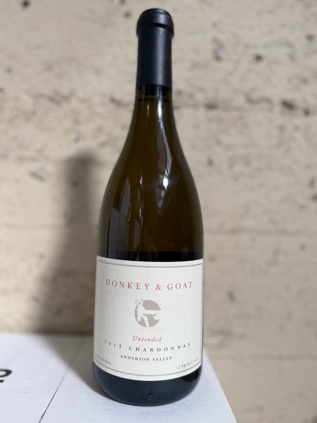 A bottle of 2012 Untended Chardonnay against the winery's concrete wall